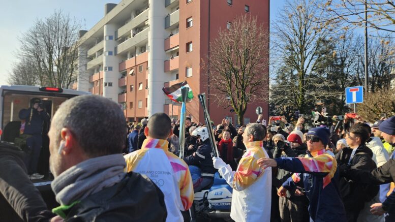 Il passaggio della fiamma olimpica tra due tedofori nella tappa di Segrate verso Milano Cortina 2026